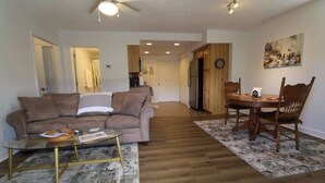 A living room with a sofa, coffee table, and dining area with chairs and a table. - Amazing View, EV Charger, Walk to Banner Elk (Banner Elk)