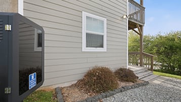 A building with a wooden deck, a window, and a sign indicating an electric vehicle charging station.