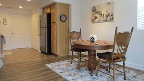 A dining area with a wooden table and chairs, a clock on the wall, and a kitchen in the background. - Amazing View, EV Charger, Walk to Banner Elk (Banner Elk)