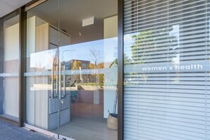 A building entrance with a glass door, a sign reading 'physiotherapy,' and a window with 'women's health' text. - Elevated Stay with Refined Interiors and Courtyard (Barton)