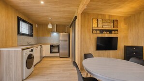 Een moderne keuken met een wasmachine, een koelkast en een eethoek met een tafel en stoelen.