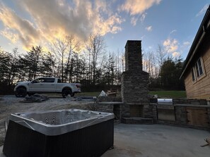 A hot tub, stone fireplace, and a truck in a backyard. - The Sycamore (Mount Nebo)