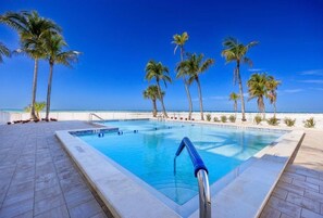 A swimming pool with clear blue water, surrounded by palm trees and a view of the ocean. - 
NEW Gulf‑Front 2BR-2BA - Direct View of Pool-Beach-Gulf (Fort Myers Beach)