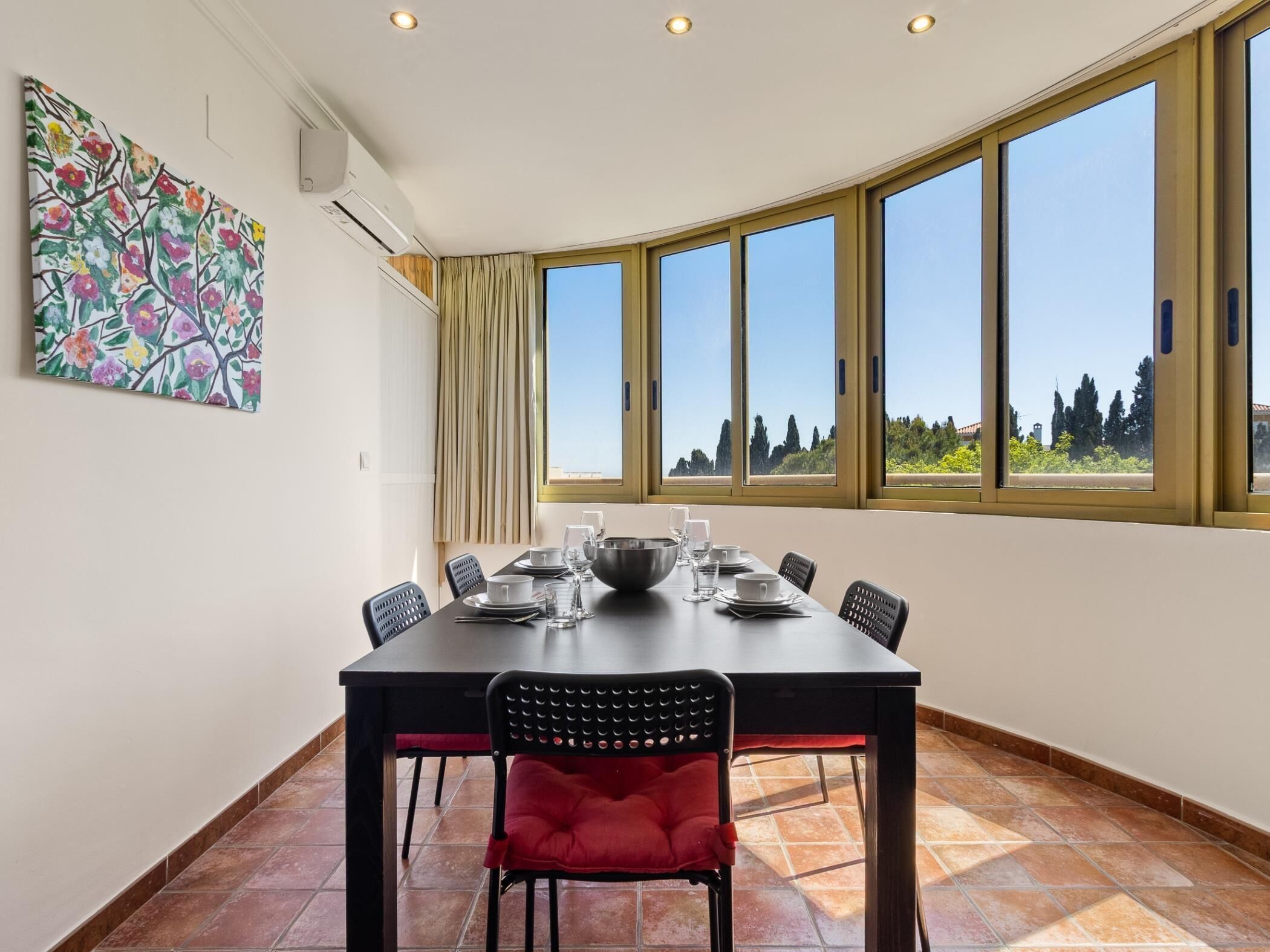 A dining area with a table set for four, large windows, and a ceiling fan.