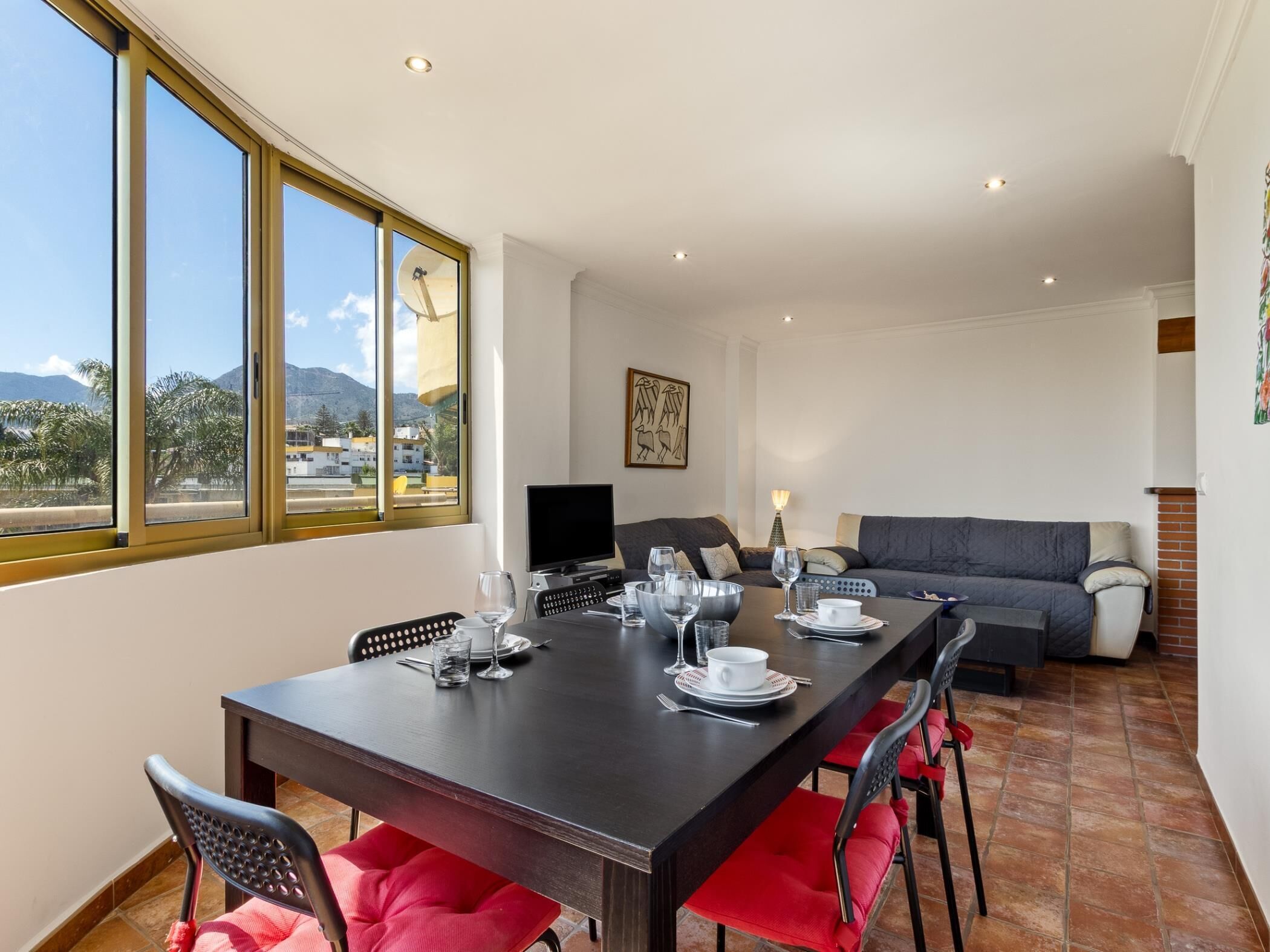 Un comedor con una mesa larga, sillas y un sofá.