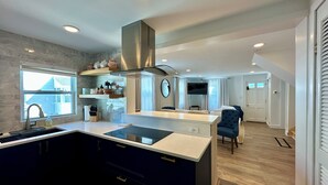 A modern kitchen with a central island, built-in appliances, and a dining area with a blue upholstered chair. - Charming 3-bedroom beach cottage in beautiful Fairfield with AC (Fairfield)