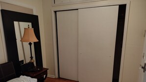 A bedroom with a bed, a nightstand, a lamp, a wardrobe, and a door. - Enjoyable 1-bedroom apartmen
t with AC in vibrant Brooklyn (Brooklyn)