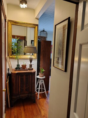 A hallway with a wooden cabinet, a mirror, a lamp, and a potted plant.