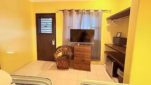 Een kamer met een bed, een televisie, een houten kast en een stoel.
