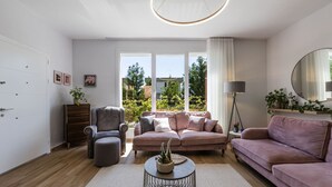 A modern living room with a sofa, armchair, and a coffee table with a plant. - Coastal Bloom Villa Garden BBQ (Ishëm)