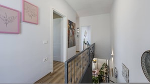 A staircase with a metal railing, a door at the top, and two framed botanical drawings on the wall. - Coastal Bloom Villa Garden BBQ (Ishëm)