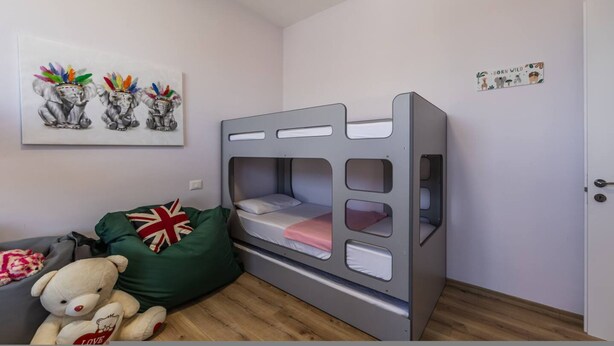 A child's room with bunk beds, a teddy bear, a green cushion, and a wall art piece. - Coastal Bloom Villa Garden BBQ (Ishëm)