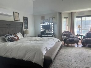 A bedroom with a large bed, a vanity with lights, a chair, and a window. - Cozy 1-bedroom house in lovely Arlington with AC (Arlington)