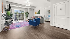 A spacious living room with a blue armchair, a grey sofa, and a large window. - Prime SLC - Airport - Convention - Hot tub (Salt Lake City)