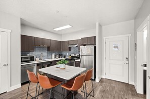 Une cuisine moderne dotée d’un îlot central, d’appareils électroménagers en acier inoxydable et de meubles en bois.