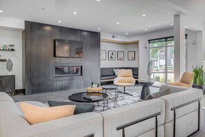 Un salon moderne comprenant un canapé, des fauteuils, une table basse et une cheminée.