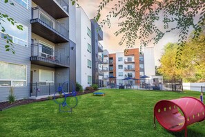 A modern apartment complex with balconies, a playground, and a red slide.