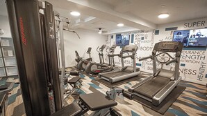 A gym with various exercise equipment, including treadmills, elliptical machines, and weight machines.