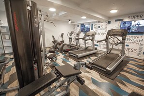 Uma academia com diversos equipamentos de exercício, incluindo esteiras, elípticos e aparelhos de musculação.
