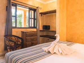 Une chambre à coucher avec un lit, une chaise, un bureau, une télévision et une fenêtre.