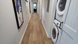 Ein Flur mit Holzboden, einer Waschmaschine und einem gerahmten Bild an der Wand.