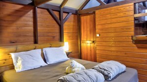 A wooden room with a bed, a nightstand, and a window. - Cozy cottage "Cocotier" w/pool in the complex (Cul de Sac)