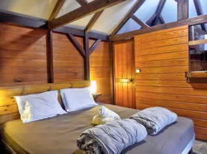 Ein Zimmer mit Holzboden, einem Bett, einem Nachttisch und einem Fenster.