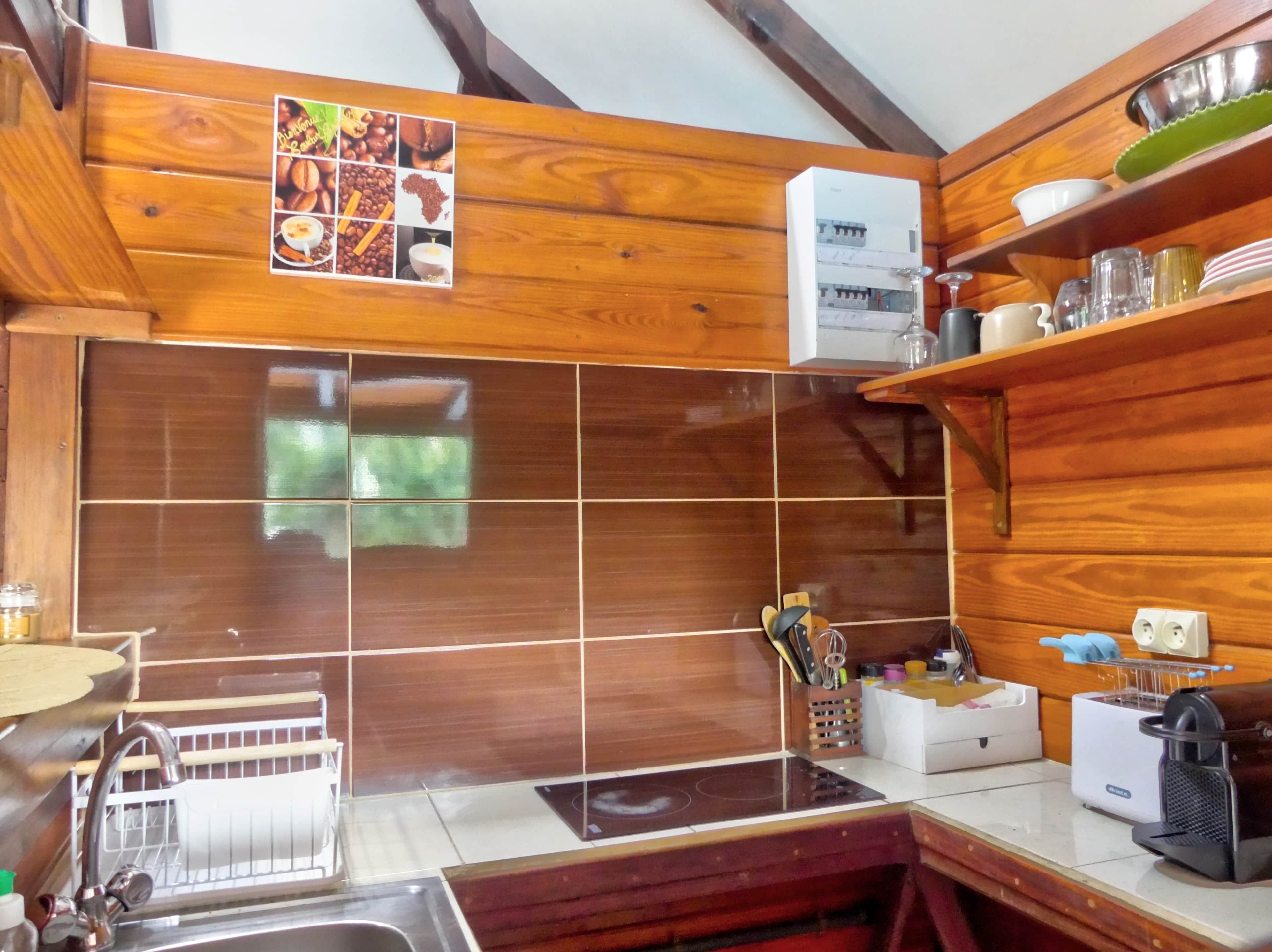 A kitchen with wooden cabinets, a tiled backsplash, a coffee machine, and a sink.