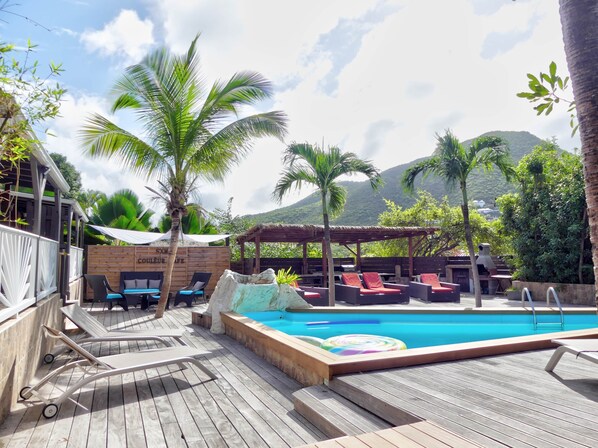 A poolside area with lounge chairs, a hot tub, and a wooden deck.