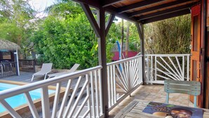 A covered outdoor area with a pool, lounge chairs, and a table with a coffee pot and cup. - Cozy cottage "Cocotier" w/pool in the complex (Cul de Sac)