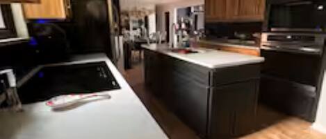 A modern kitchen with a central island, wooden cabinets, and built-in appliances.