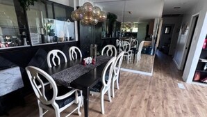 A dining area with a black table and white chairs, a wooden floor, and a modern pendant light.