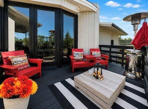 An outdoor deck with red chairs and a wooden table, a grill, and a potted plant. - Dallas Cowboys Farmhouse Retreat • Sleeps 10 • By AT&T Stadium (Grand Prairie)
