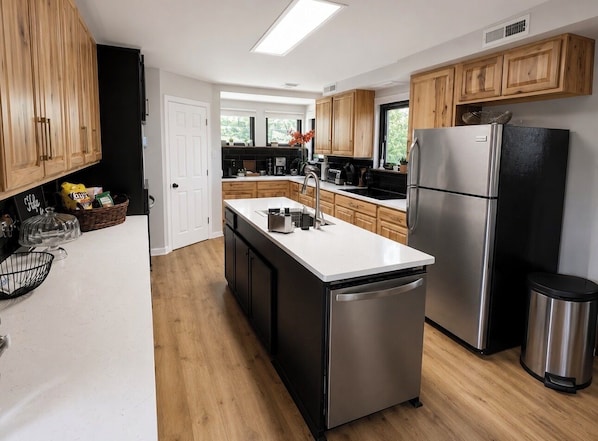 A modern kitchen with wooden cabinets, stainless steel appliances, and a central island.