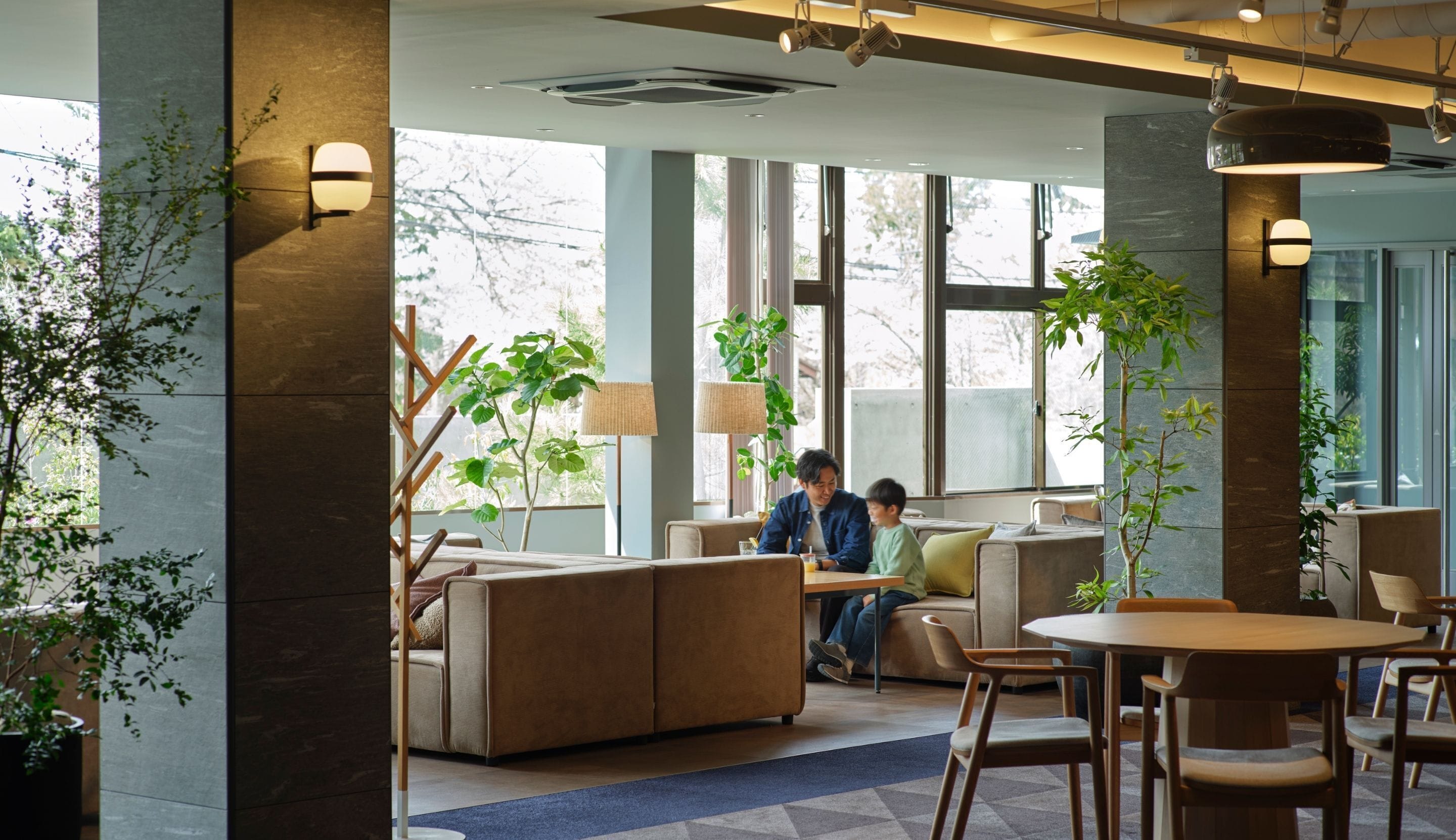 A modern interior with seating areas, large windows, and indoor plants.