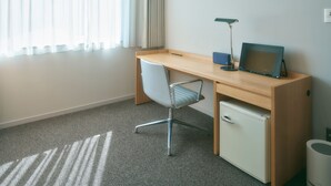 Quarto com escrivaninha, cadeira, computador, luminária e um pequeno armário.