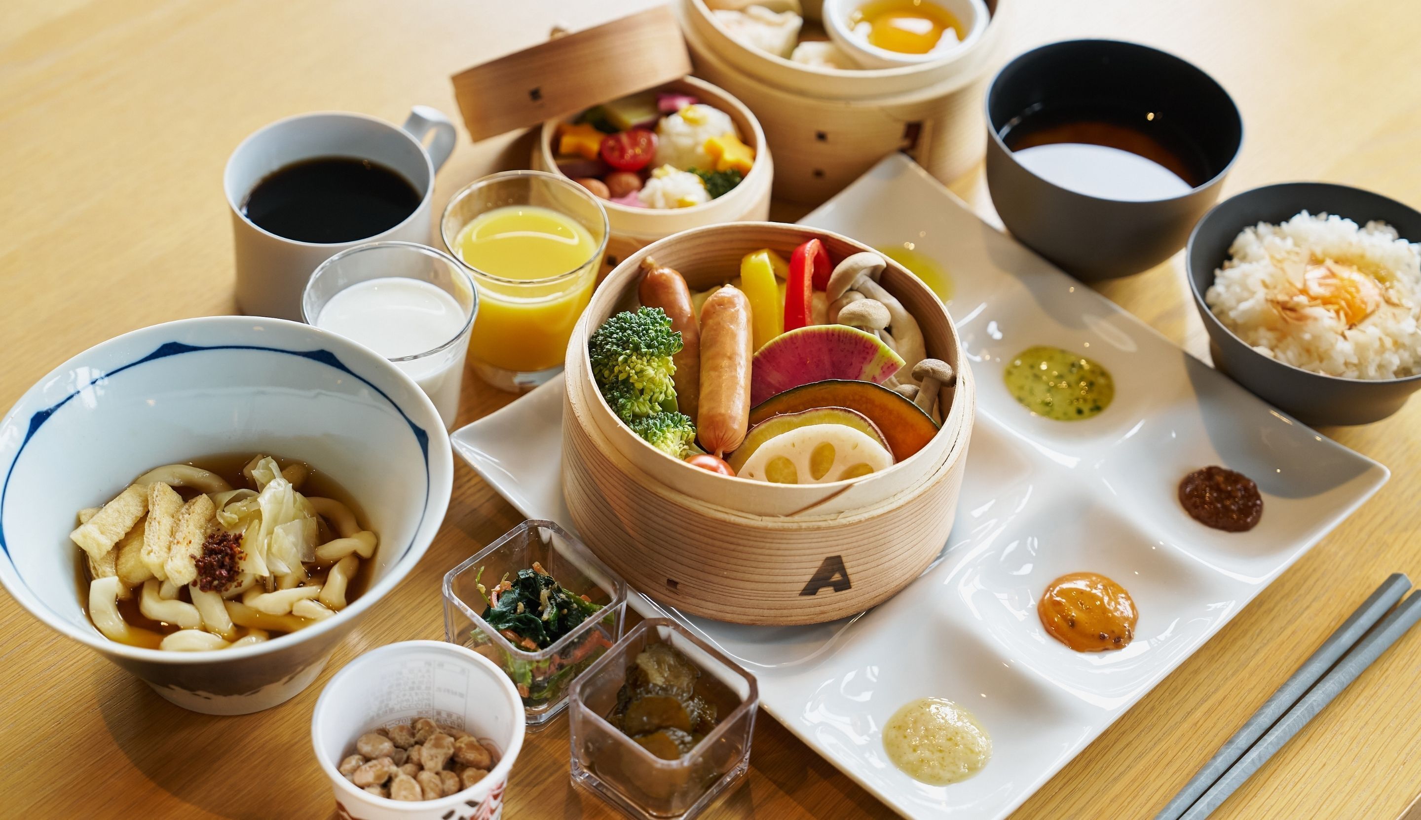A variety of Japanese dishes including sushi, rice, and soup, arranged on a wooden table.