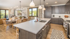 Una cucina moderna con un'isola grande, mobili scuri e una zona pranzo con sedie e tavolo in legno.