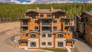 Un edificio in legno a più piani con facciata in pietra, balconi e vialetto.