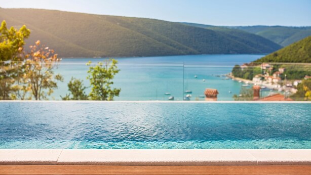 A swimming pool with a view of a lake and hills.