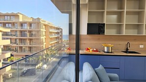 Un appartement moderne doté d’un balcon, d’une cuisine avec un plan de travail en bois et offrant une vue sur d’autres immeubles.