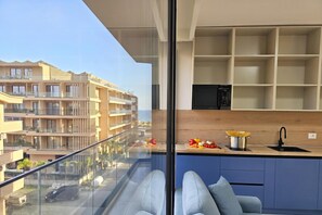A modern apartment with a balcony, a kitchen with a wooden countertop, and a view of other buildings. - Pool Side Apartment, Vlore, Albania (Vlore)