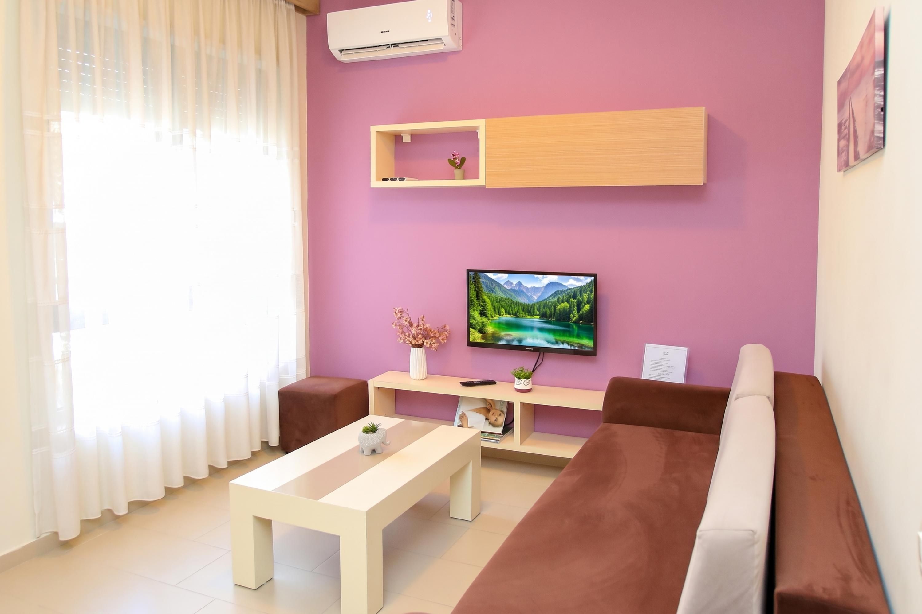 A modern living room with a flat-screen TV, a sofa, a coffee table, and a small side table with a vase.