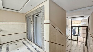 A hallway with a marble floor, two elevators, and a staircase leading to an outdoor area. - 308A, Diamond Two Bedroom Apartment, Vlore, Albania (Vlore)