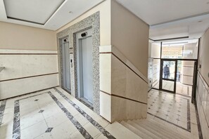 A hallway with a marble floor, two elevators, and a staircase leading to an outdoor area. - 308A, Diamond Two Bedroom Apartment, Vlore, Albania (Vlore)