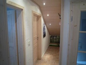 Ein Flur mit Holztüren, Holzboden und einer Decke mit eingelassener Beleuchtung.