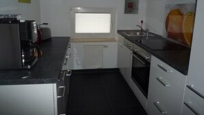 A compact kitchen with a stove, oven, sink, and a window with blinds. - Oberm Dorp in Winterberg-Hildfeld by Interhome (Winterberg)