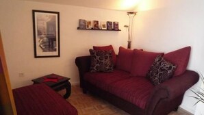 A living room with a sofa, a small table, a floor lamp, and a framed picture on the wall. - Oberm Dorp in Winterberg-Hildfeld by Interhome (Winterberg)