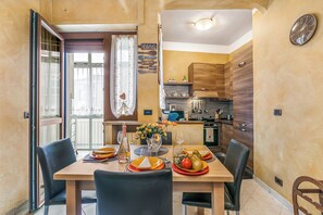 A dining area with a table set for four, a kitchen in the background, and a wall clock. - La Torinese, Torino, Italy (Torino)