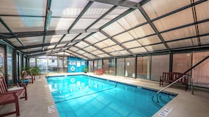 Una piscina interior amb línies de separació ben definides, un senyal de seguretat i una cadira de fusta.